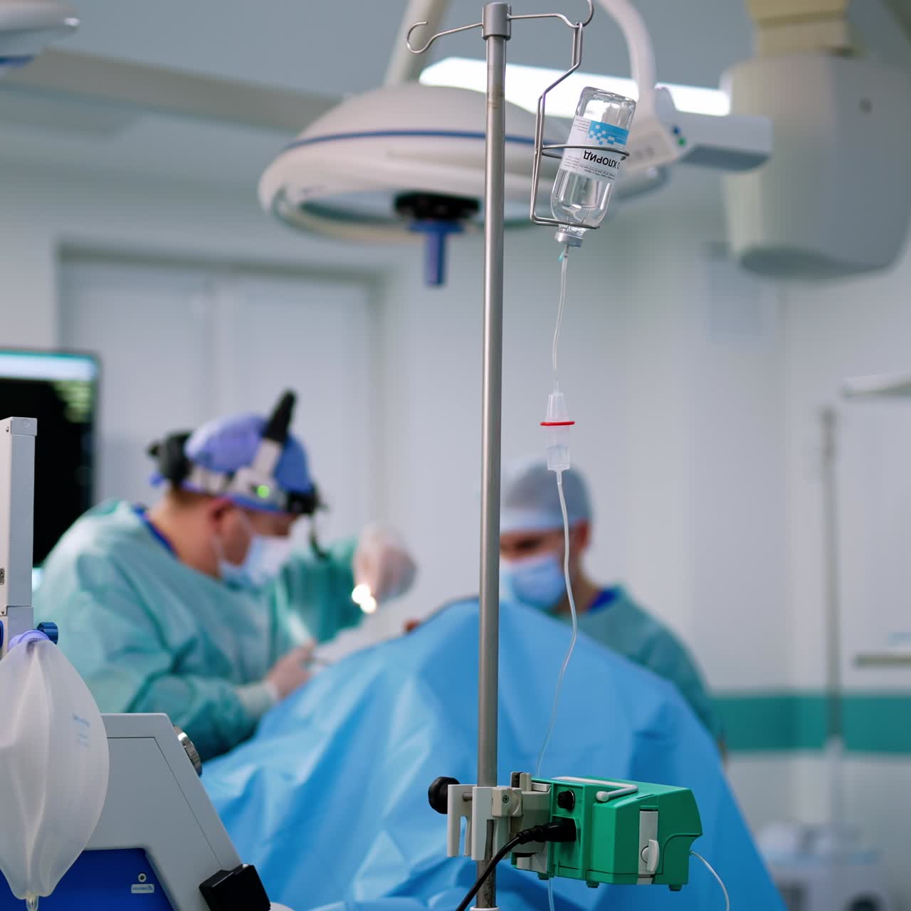 Una bottiglia con soluzione salina è sopra il supporto del contagocce. Un chirurgo esegue un'operazione nasale.