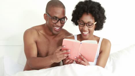 smiling young couple reading book together