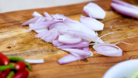 close-up of hands slicing shallots on a wooden board with vibrant lighting and fresh ingredients