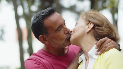 close-up of happy senior couple hugging and kissing in park