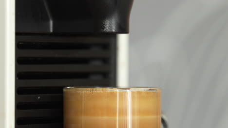 disparo en primer plano de una taza de café que se llena hasta el borde por la máquina de café