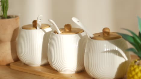 white ceramic spice jars with wooden spoons on a wooden tray