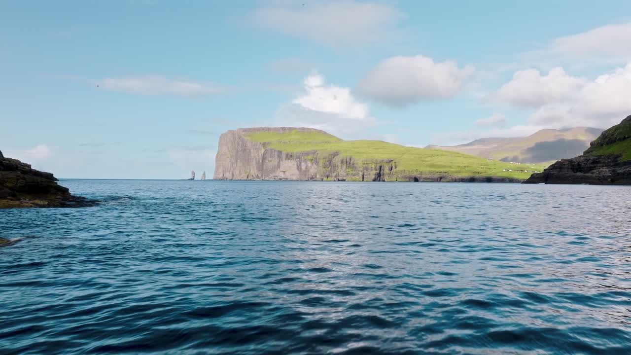 A peaceful ocean view in the Faroe Islands with lush green cliffs and clear blue skies