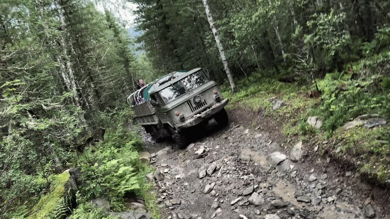 Un robusto fuoristrada 4x4 scala una pista sterrata rocciosa attraverso una fitta foresta di conifere sui Monti Altai, vicino a Gorno-Altaysk, Repubblica dell'Altaj, Russia, concetto di viaggio avventura.