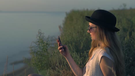 mujer usando el teléfono al atardecer junto al río