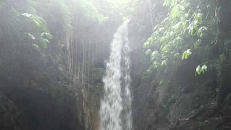 a dolly shot of a pool of water, created by a small waterfall, surrounded by rocks and cliffs in the jungle of bai