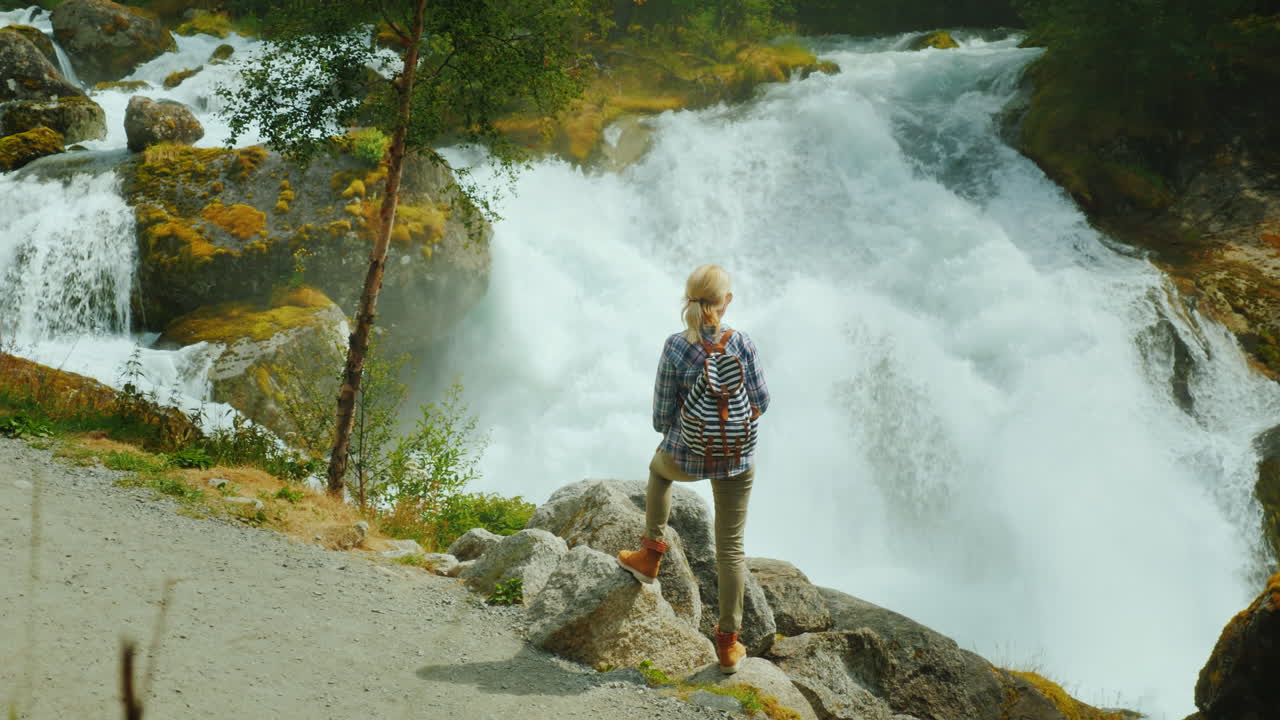 여행자는 briksdal 빙하에서 시작된 폭풍우가 치는 산 강을 존경합니다 장엄한 장면