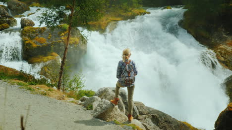 the traveler admires the stormy mountain river originating in the briksdal glacier the majestic scen
