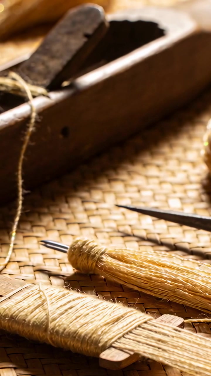 Vertical video: Shifting framing, bobbin and awl revealing twine and plane on mat, showing texture