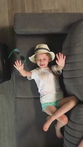 happy brother and sister spend time at home. little boy plays with aeroplane while elder sister dances with hands on sofa waiting for flight upper view