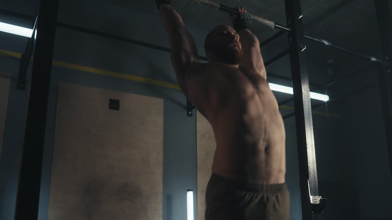 hombre realizando pull-ups en un gimnasio