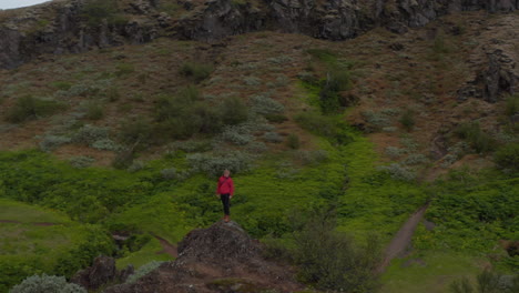 Birds-eye-sportive-man-standing-peak-in-cloudy-day-in-northern-icelandic-highlands.-Amazing-aerial-view-of-hikers-standing-on-top-of-hill-enjoying-Aldeyjarfoss-waterfall-highlands-in-northern-Iceland