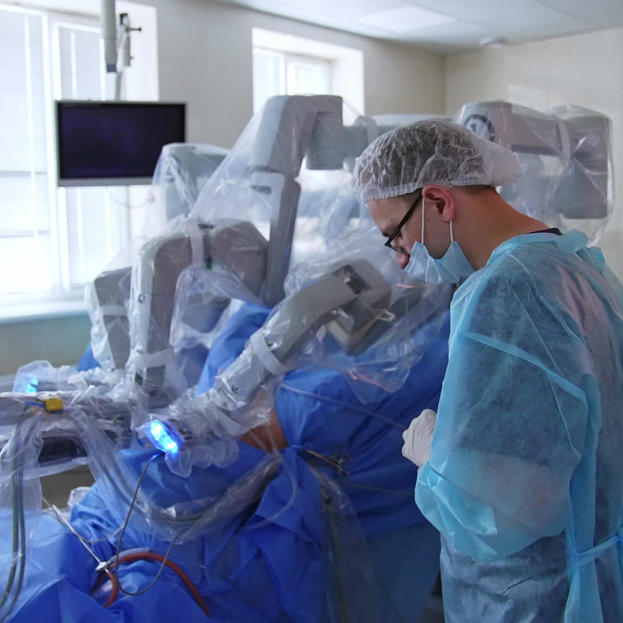 Advanced robotic equipment performing surgical operation in modern operational theatre. Surgeon doctor follows the process at the monitor
