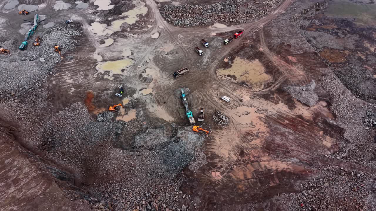 Workers move granite and heavy equipment in industrial quarry site