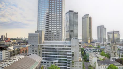 sweeping view of a modern city skyline under a clear blue sky, characterized by tall steel and glass skyscrapers with a distinct blue, curved edifice dominating the scene