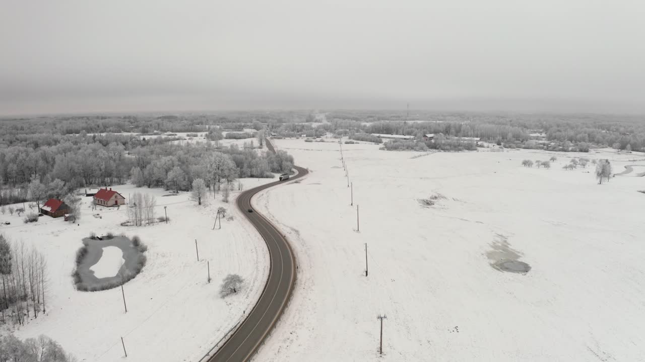 Aerial drone view of a winding highway road through a frozen winter landscape with icy trees. Frost on the trees after extreme cold.