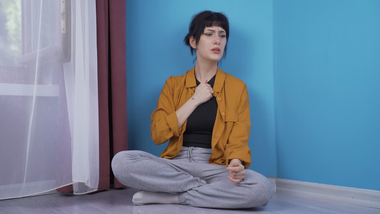 벽  ⁇ 에 앉아 있는 젊은 여자는 자기 자신에게 화를 내고 있습니다.