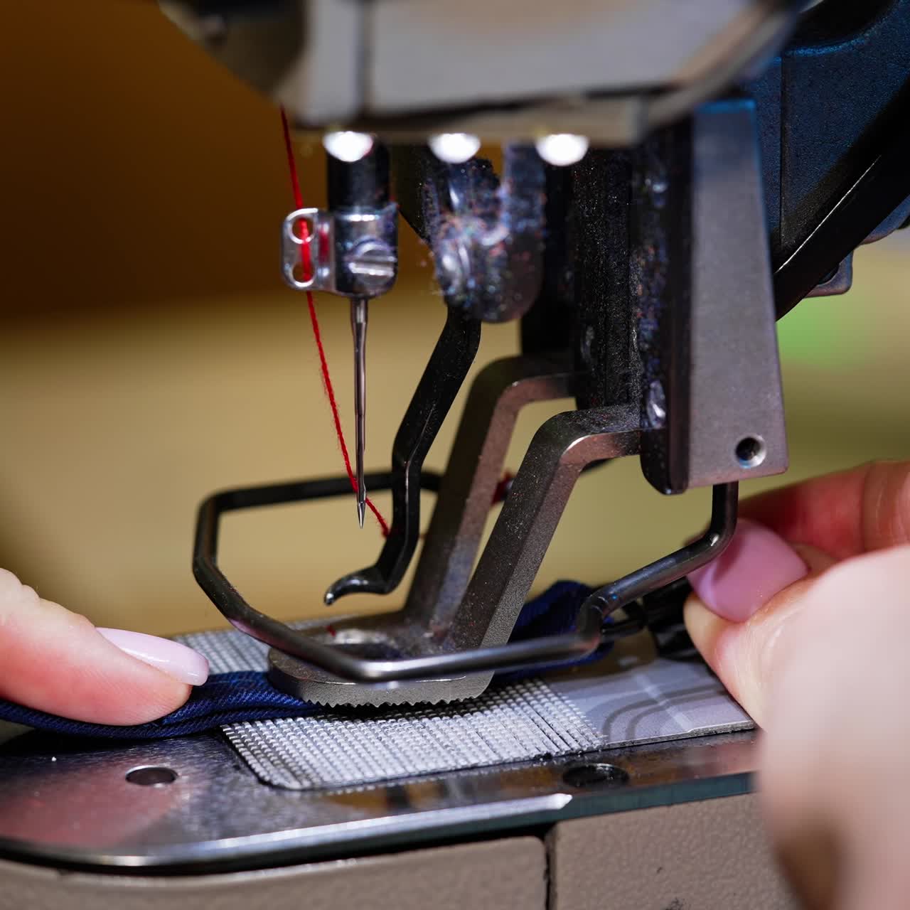 Woman using sewing machine in factory. Female hands working on tailoring industrial fabric
