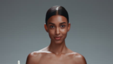woman, serum bottle and face in studio for shine