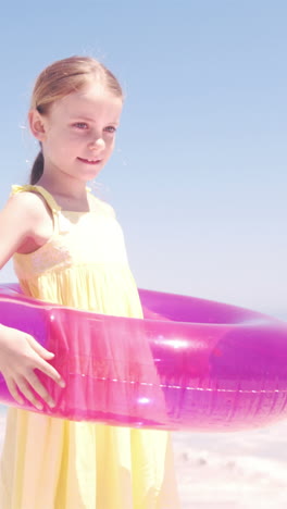 little girl playing with her buoy on the beach with her parents