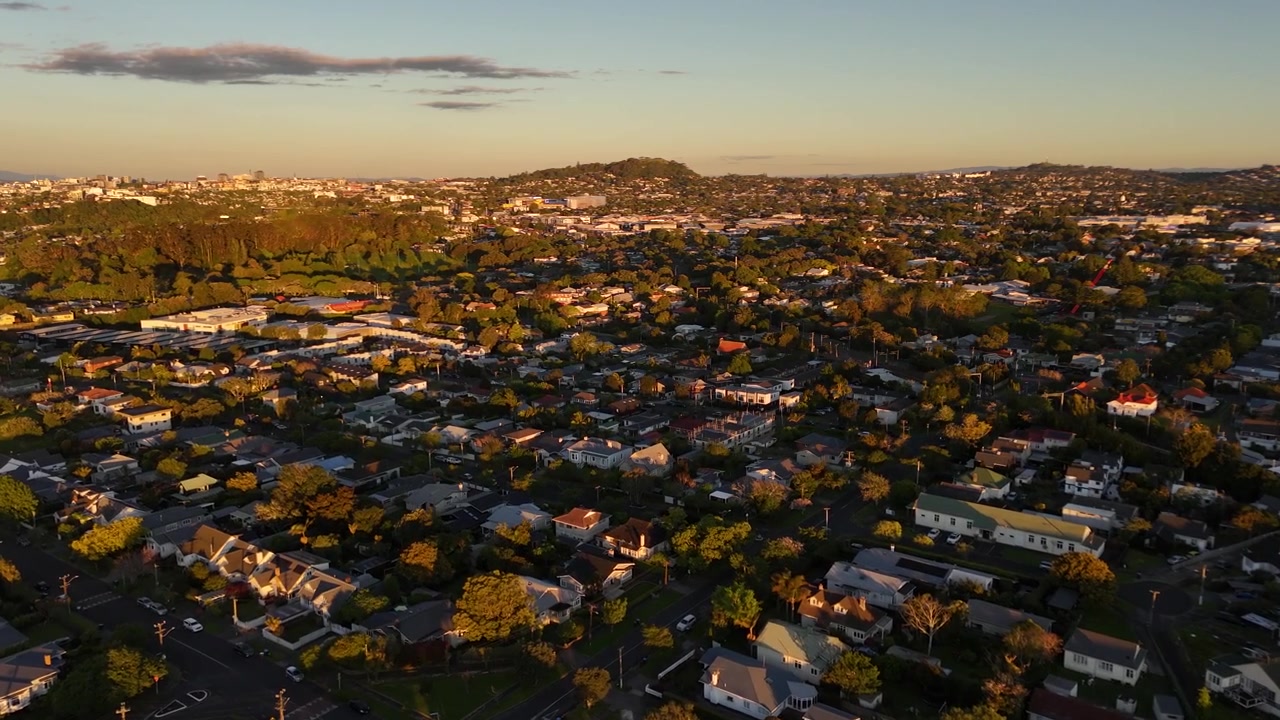 Residential houses and green hills in Mount Albert at sunset in Auckland, New Zealand. Aerial drone view