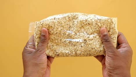 closeup of hands holding a bag of rolled oats