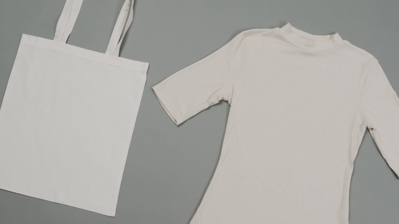 회색 배경에 색 가방과 티셔츠의 클로즈업, 복사 공간, 느린 동작