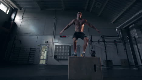 man performing box jumps in gym