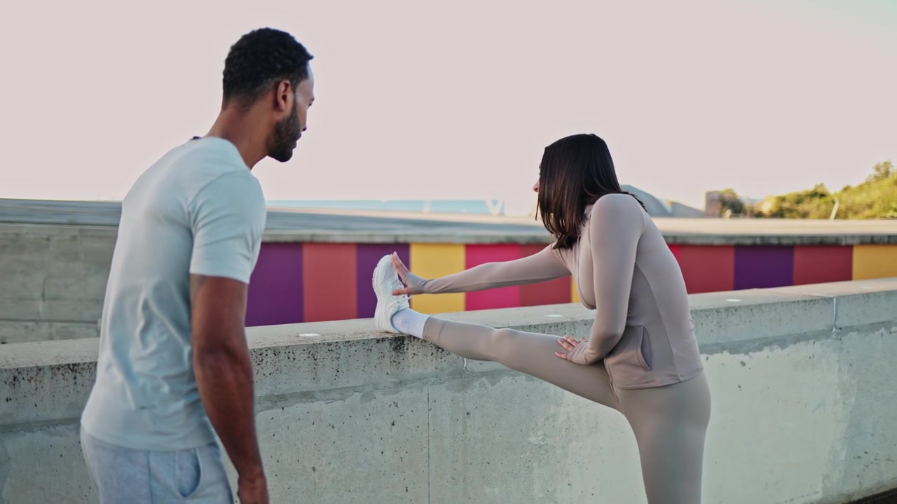Personal Trainer Coaching Woman Stretching Leg on Concrete Wall