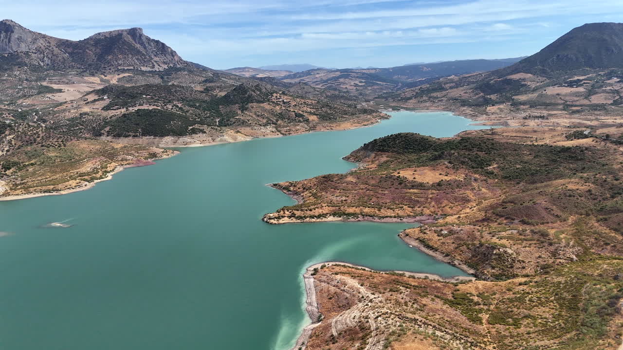 Aerial drone footage of Zahara-El Gastor reservoir surrounded by mountains and blue water in Andalusia, southern Spain