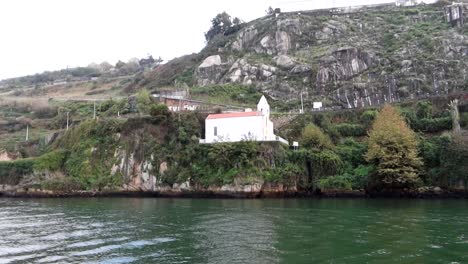 Capilla-Blanca-Solitaria-En-Un-Pequeño-Acantilado-Frente-A-Las-Aguas-Esmeralda-Del-Río-Duero-En-Oporto