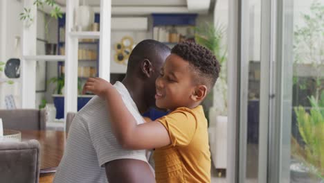 video of happy african american father and son hugging at home