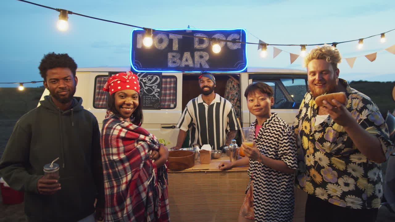 Ritratto di gruppo di amici allegri vicino a un food truck a un festival estivo