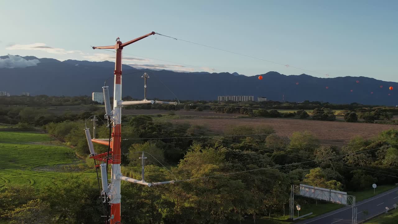 Panoramic view of RN40 highway connecting Ibagué and Armenia, Colombia, featuring a large electricity transmission tower and surrounding landscape under clear sky.