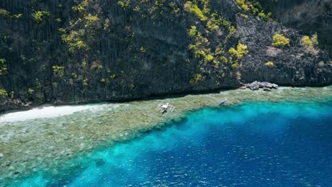 aerial circling footage of tourist boats hover over coral reef near matinloc shrine. el nido, palawan philippines