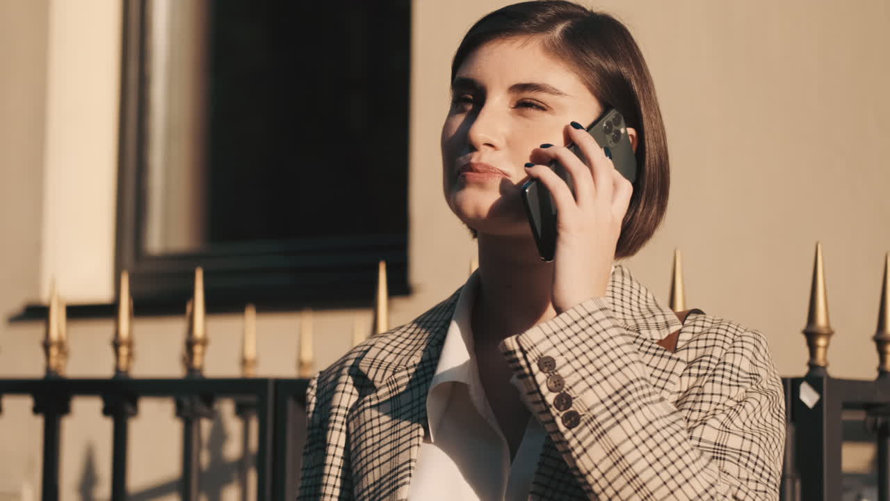 스타일리시한 여성이 야외에서 비즈니스 통화를 하고 있습니다.