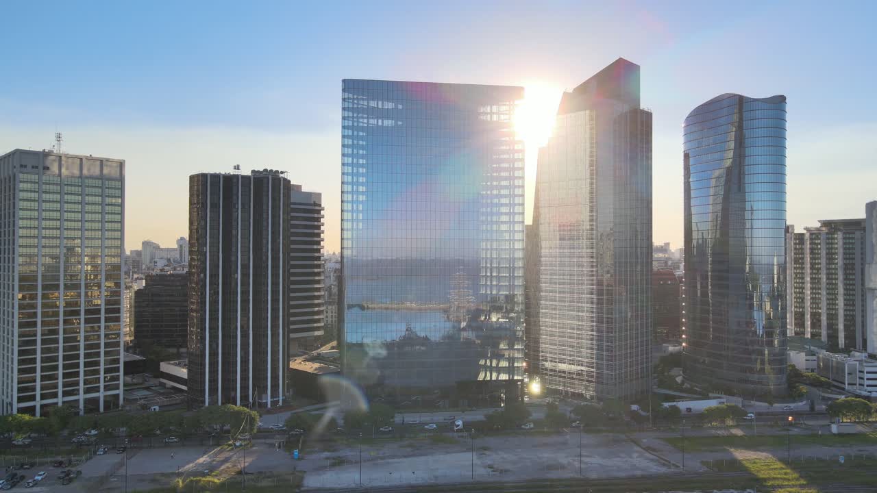 Panorâmica aérea para a esquerda dos arranha-céus envidraçados de Puerto Madero perto da autoestrada Paseo del Bajo ao pôr do sol, Buenos Aires.