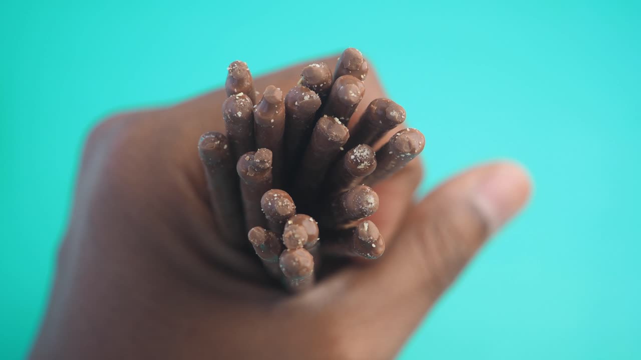 Hand Holding Chocolate Covered Biscuit Sticks