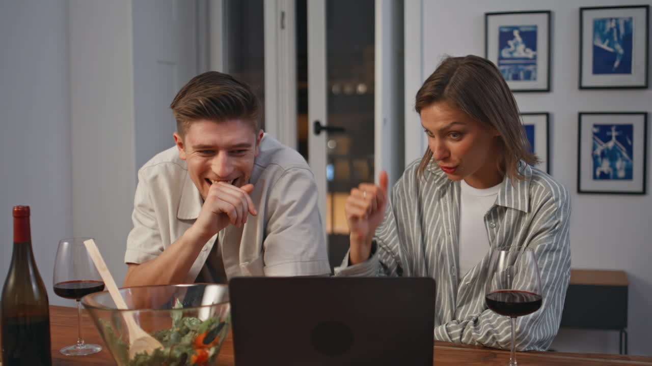 Laughing couple watching laptop in evening closeup. Cheerful pair enjoying funny
