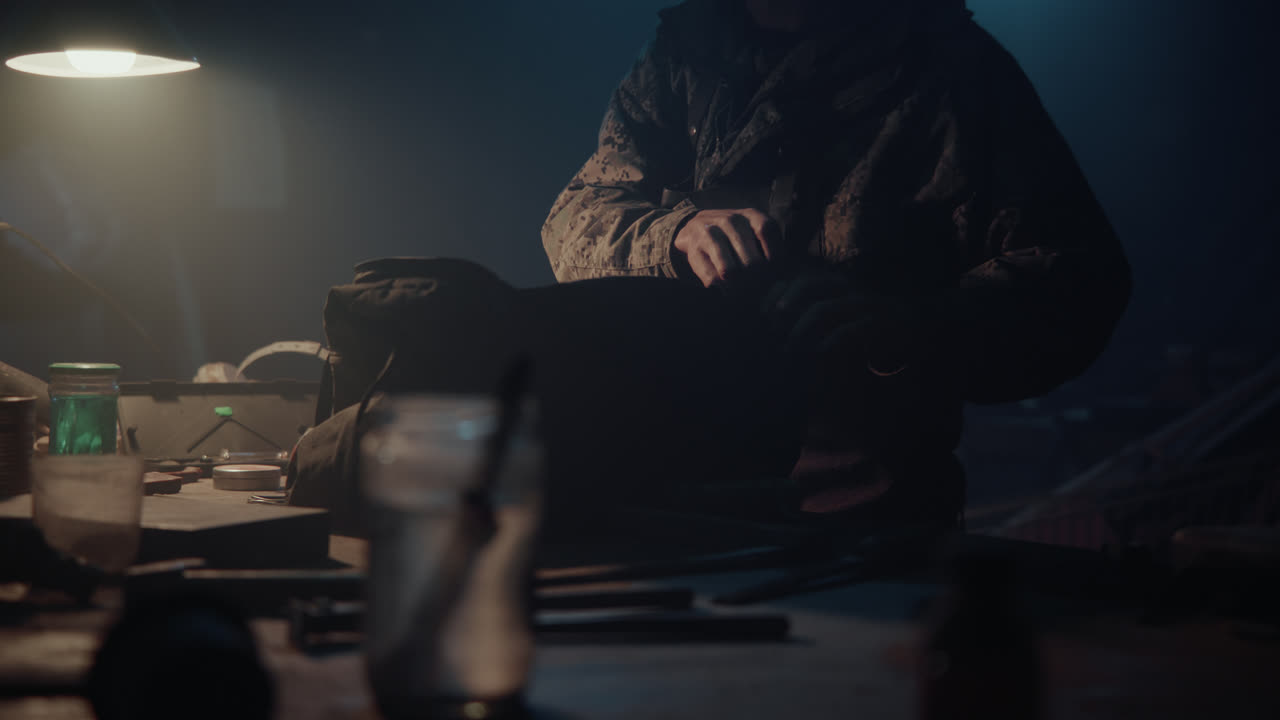 A bombmaker puts a bomb in the bag in his workshop at night