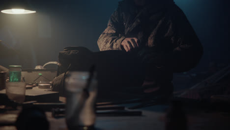 a bombmaker puts a bomb in the bag in his workshop at night