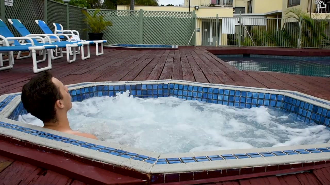 Person entering a bubbling jacuzzi in a small resort.