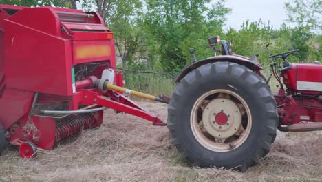 recolección de paja después de las cosechas de trigo. herramientas de heno en acción agricultores tractor tira de la embaladora.