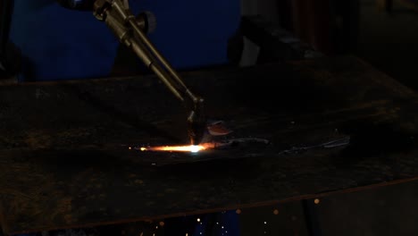 oxyfuel cutting a piece of metal in super slow motion with industrial background