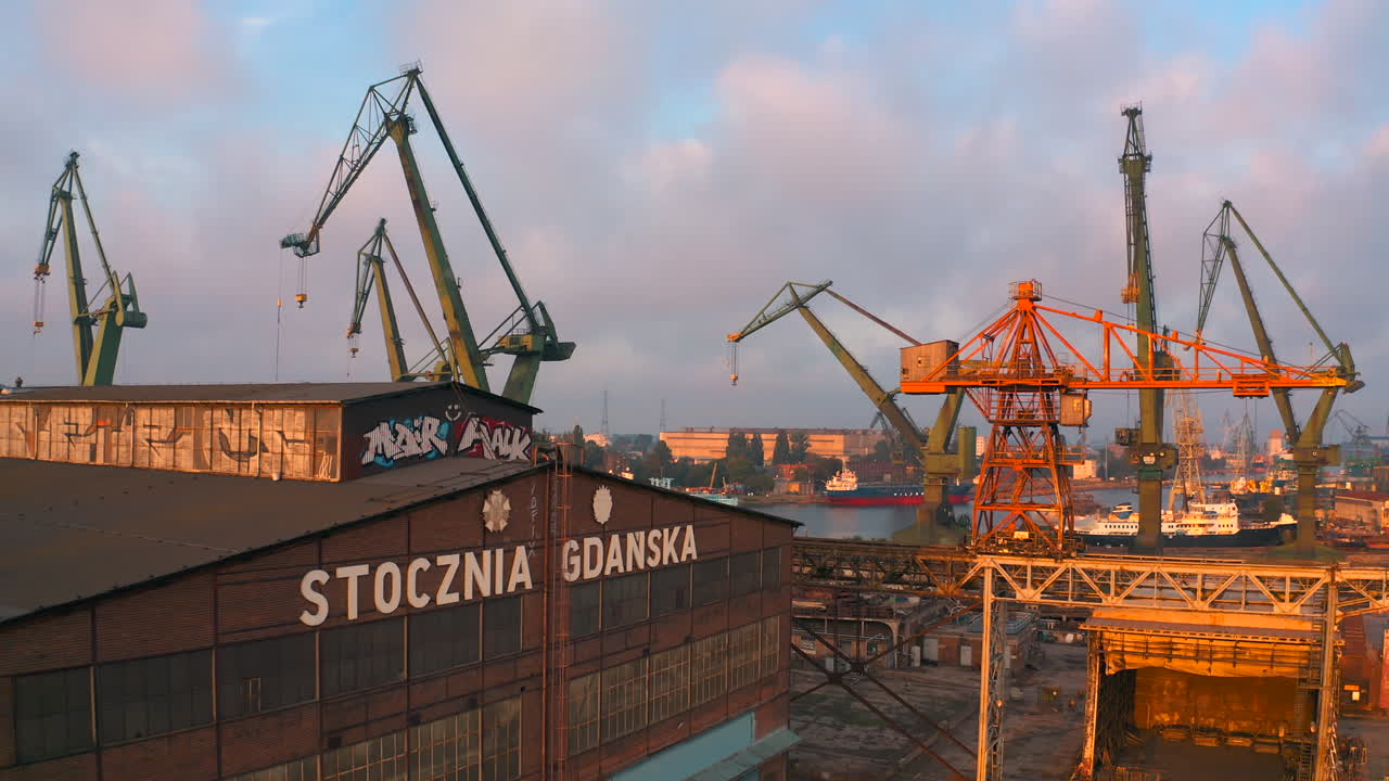 Aerial view of drone flying above shipyard in Gdansk at the sunset with cranes in the background