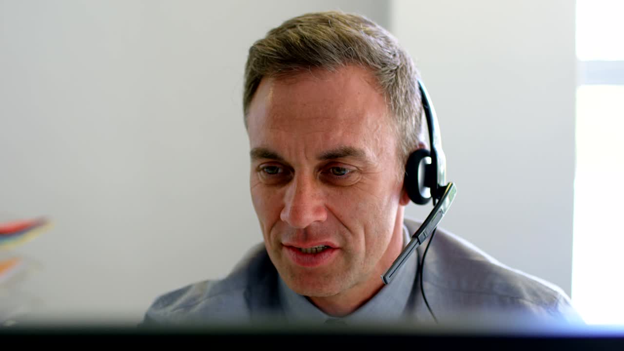 hombre de negocios hablando en auriculares mientras trabaja en computadora 4k