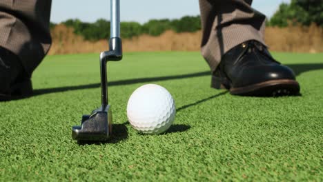 un hombre de negocios preparándose para un putt en un campo de golf.