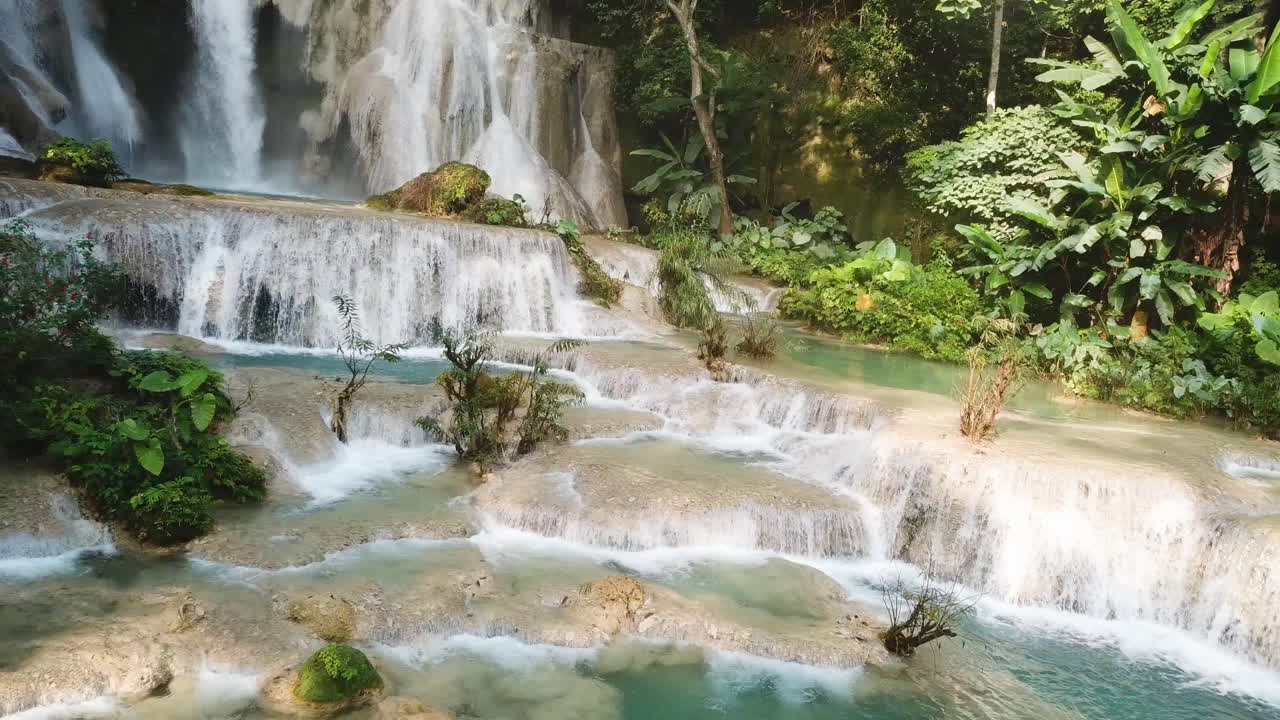 Magica piscina naturale sotto una cascata esotica nella foresta pluviale, ripresa aerea panoramica.
