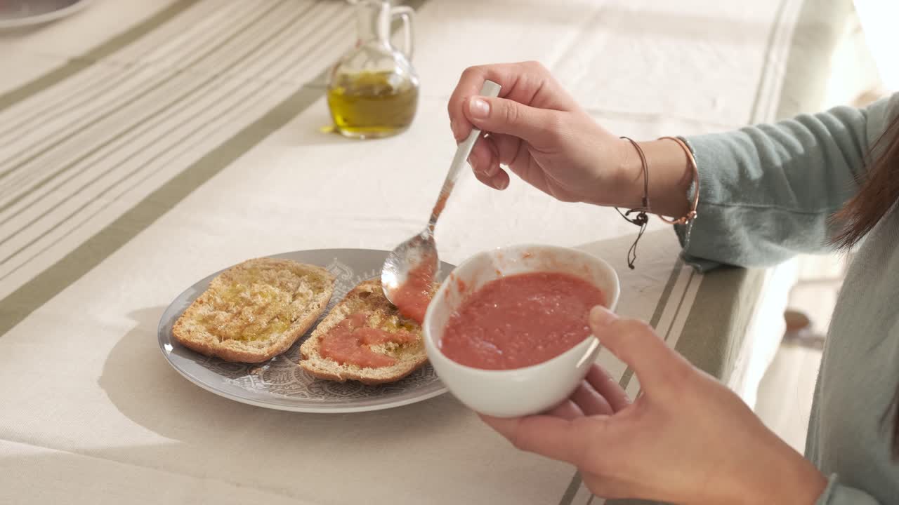 Unrecognizable person spreading tomato on the bread sitting on a table