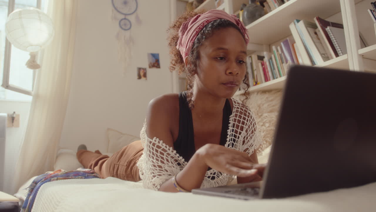 Young Black Girl Lying on Bed and Using Laptop